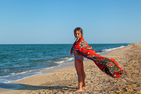 Happy smiling little girl playing with an inflatable ball on the beach by the sea shore in summerの写真素材
