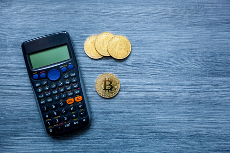 Gold bitcoin cryptocurrency, bitcoin coins, and calculator on wooden background, bitcoin mining conceptの写真素材