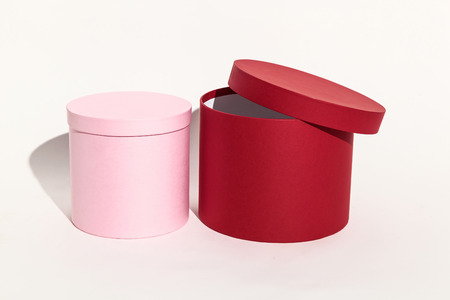 Beautiful pink and red round gift box for packing a surprise with a closed lid close-up on a white background.の写真素材