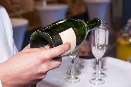 The waiter pours champagne into glasses from a bottle in a restaurant. Catering, banquetの写真素材