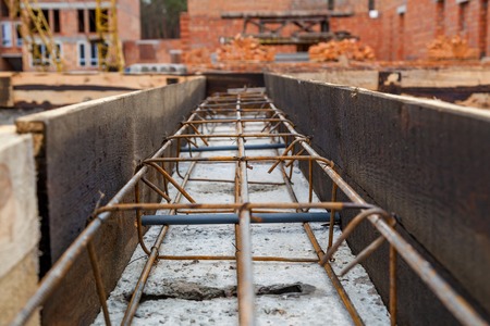 Metal structures for concrete structures. Construction site, tools, wheel barrow, sand and bricks at...