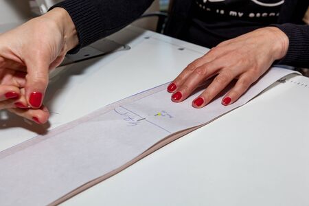 Female tailor hands with cloth, pattern and needle in the workshopの写真素材