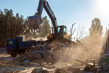 The excavator loads the remains of the destroyed building in the car