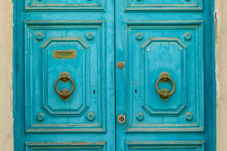 Texture of an old wooden wooden door with unusual metal handles on the island of Malta