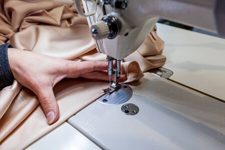 Close-up photo of sewing chocolate fabric.Woman sews fabric by a sewing machine