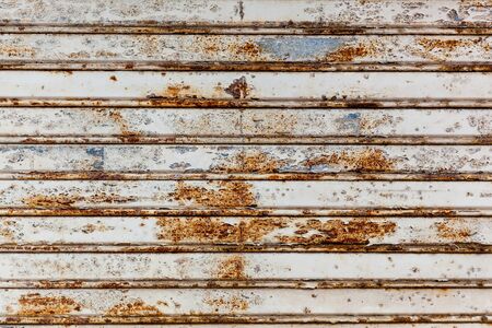 Close-up view of the old rusty plate which hangs on the wall of the building.