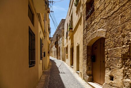 A beautiful narrow lane with typical Maltese architecture. The wall of the building decorated a stone sculpture of saint.の写真素材