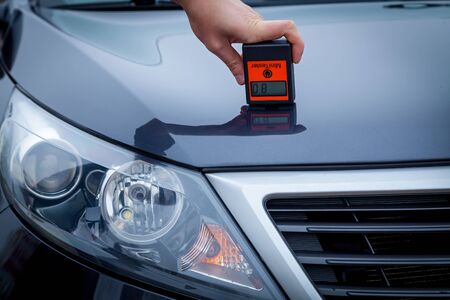 Measuring the thickness of the car paint coating in black color using a paint thickness gauge.