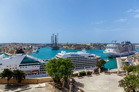 A beautiful panorama of a sea with luxury modern cruise liners near a shore of Malta on the background of a pure blue sky.の写真素材