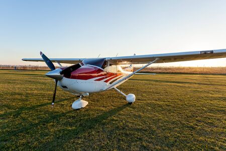 Ukraine Kiev October 11, 2018: A small aircraft of white and red colors standing on the airfield on the green grass on the background of the sky.のeditorial素材