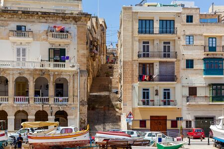 Malta Valletta June 16, 2019: The beautiful cityscape with Maltese houses near the pier. Stone stairs among modern residential buildings go down to the pier.のeditorial素材