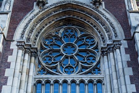 An old arched church window with decorative elements on the wall.