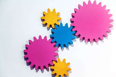 Wooden bright cogwheels on the background of a white wall. An abstract pattern or background with...