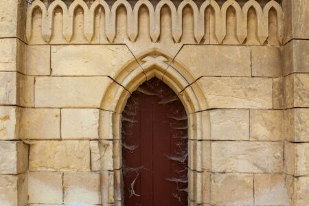 An old brick facade with a wooden church door and figured decorations.の写真素材