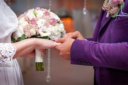 A bride putting a ring on the groom's finger during the wedding ceremony.