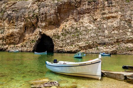A beautiful view with a white tourist boat in front of the marine cave on a sunny day. There are lots of boats near the entrance of a cave.の写真素材