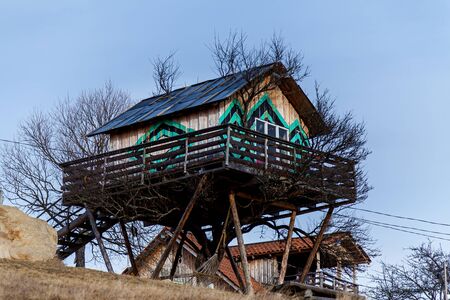 An amazing treehouse with bright decorative elements on the walls and a big white window on the background of a blue sky on an autumn day.の写真素材