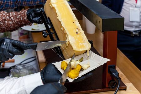 A chef is preparing a dish with raclette using a special instrument for cheese melting.の写真素材