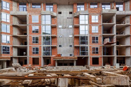 Facades of a multistory building under construction. Construction site, tools, wheel barrow, sand and bricks at new house building, cement mixer machine and accessoriesの写真素材