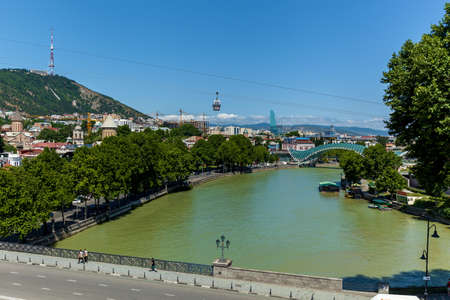 Tbilisi Georgia June 30, 2017: Pedestrian Peace Bridge over the Kura River, Narikala Fortress. Beautiful new park in the center of the old city of Tbilisi, Georgiaのeditorial素材