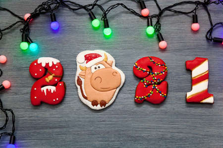 A Christmas card for the holidays. Gingerbread in the form of numbers 2021 and the symbol of the new year bull on a gray wooden background. Merry Christmas and a new year.の写真素材
