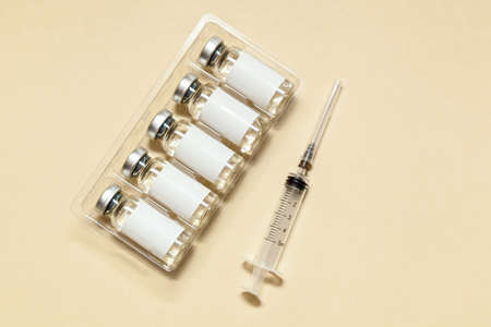 Syringe with vaccine in bubbles and stickers without inscription on a beige background. Medicine concept. Photo with place for your text and design.Novel coronavirus 2019の写真素材