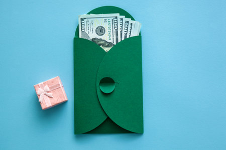 One hundred dollar bills in a green envelope on a blue background. Bribe, investment, business and...
