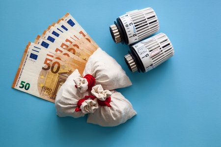 Thermostats for batteries and euro banknotes on a blue background. The concept of expensive heating costs and rising electricity prices in the winter cold season.の写真素材