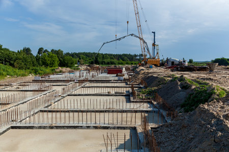 Construction site with construction equipment, rebar and foundation of a residential building. Steel...