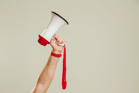 A man's hand holds a loudspeaker on a white background. The loudspeaker is a symbol of advertising, PR and promotion. The concept of alert, announcement, warning and advertising.の写真素材