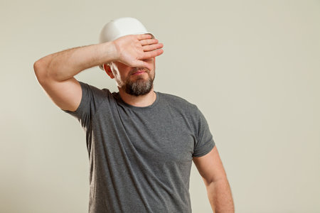 A guy in a white construction helmet, a gray T-shirt shows different gestures with his hands