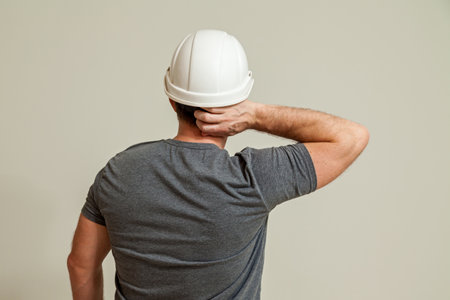 A guy in a white construction helmet, a gray T-shirt shows different gestures with his hands