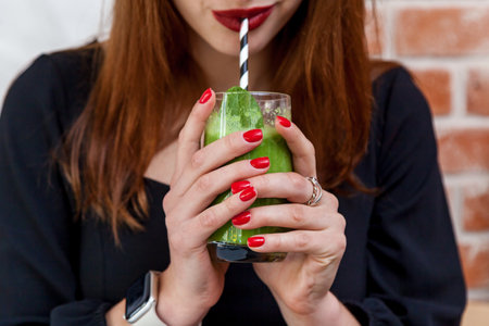 A girl in a cafe drinks a spinach, avocado and mint smoothieの写真素材