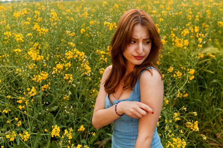 The girl has an allergic reaction to the pollen of yellow rapeseed flowers in the fieldの写真素材