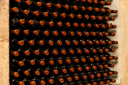 Close-up view of neatly arranged vintage wine bottles with red wax seals in a dimly lit stone cellar