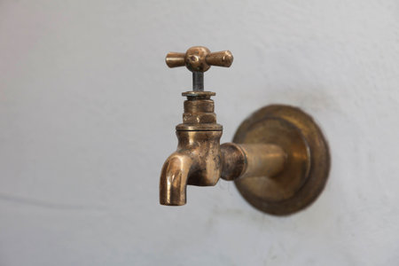 On the white wall the old brass faucet.の写真素材