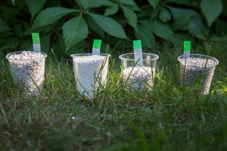 In the bright sunbeams fertilizer in plastic cups surrounded by bright green grass. On the stickers is recorded of fertilizer formula.の写真素材