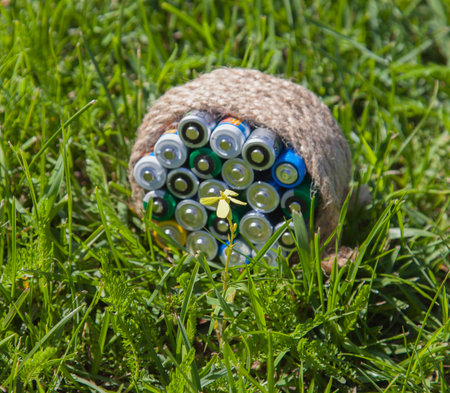 Yelow flower in a bright sunbeam in the foreground and blurred batteries wrapped a rope on the...