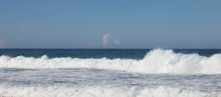 Blue sky, blue sea and pink clouds on the horizon. Surf, waves and white sea foam.の写真素材