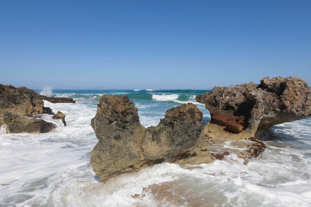 Blue sky, blue sea and rocks. Waves, surf and white sea foam.の写真素材
