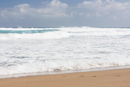 Blue sky and blue sea. Waves, white clouds and sea foam, yellow sand beach.の写真素材