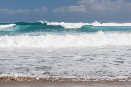 Blue sky and blue sea. Waves, white clouds and sea foam, yellow sand beach.の写真素材