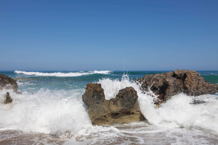 Blue sky, blue sea and waves, breaking on rocks. Surf and white sea foam.の写真素材