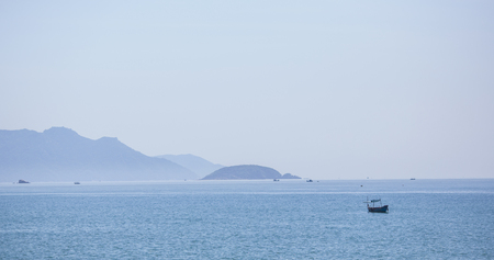 A beautiful seascape, a sailboat floating in the distance amidst majestic mountains.の写真素材