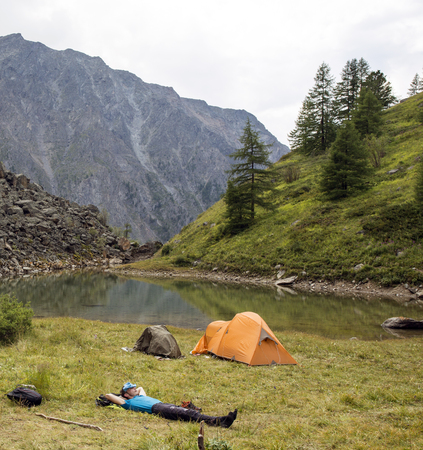 In the forest the tourist lies near the tentの写真素材