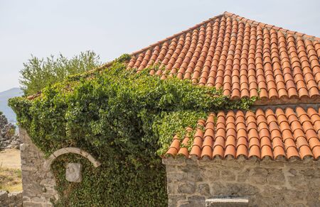 Fragment of the tile roof lit with the sun. A roof against the background of the bright blue skyの写真素材