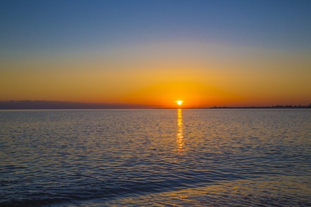 Picturesque bright sunset over the waves of the blue sea in the summer evening. reflection on the water.の写真素材