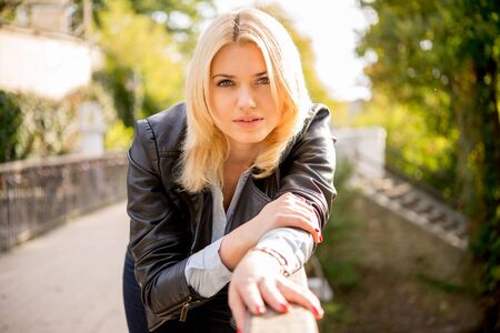 beautiful blond girl leans on the railing of the bridgeの写真素材