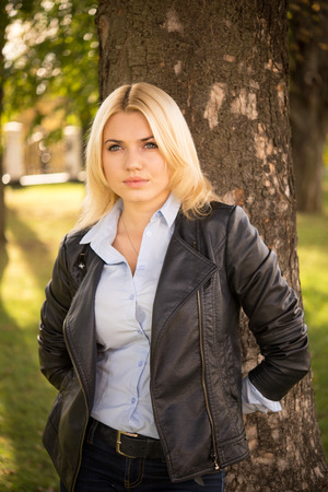 pretty blond girl standing near a treeの写真素材