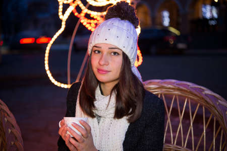 beautiful girl sitting outdoors in winter with a cupの写真素材